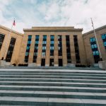 Fachada do edifício do Federal Reserve dos Estados Unidos, vista de baixo, com bandeiras americanas e céu nublado