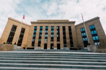 Fachada do edifício do Federal Reserve dos Estados Unidos, vista de baixo, com bandeiras americanas e céu nublado