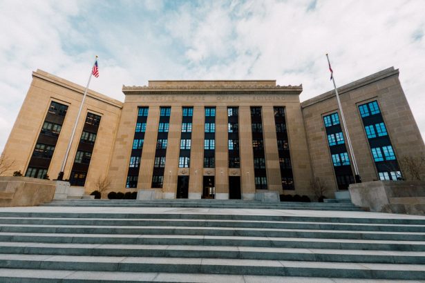 Fachada do prédio do Federal Reserve nos Estados Unidos, vista de baixo, com bandeiras americanas ao redor.